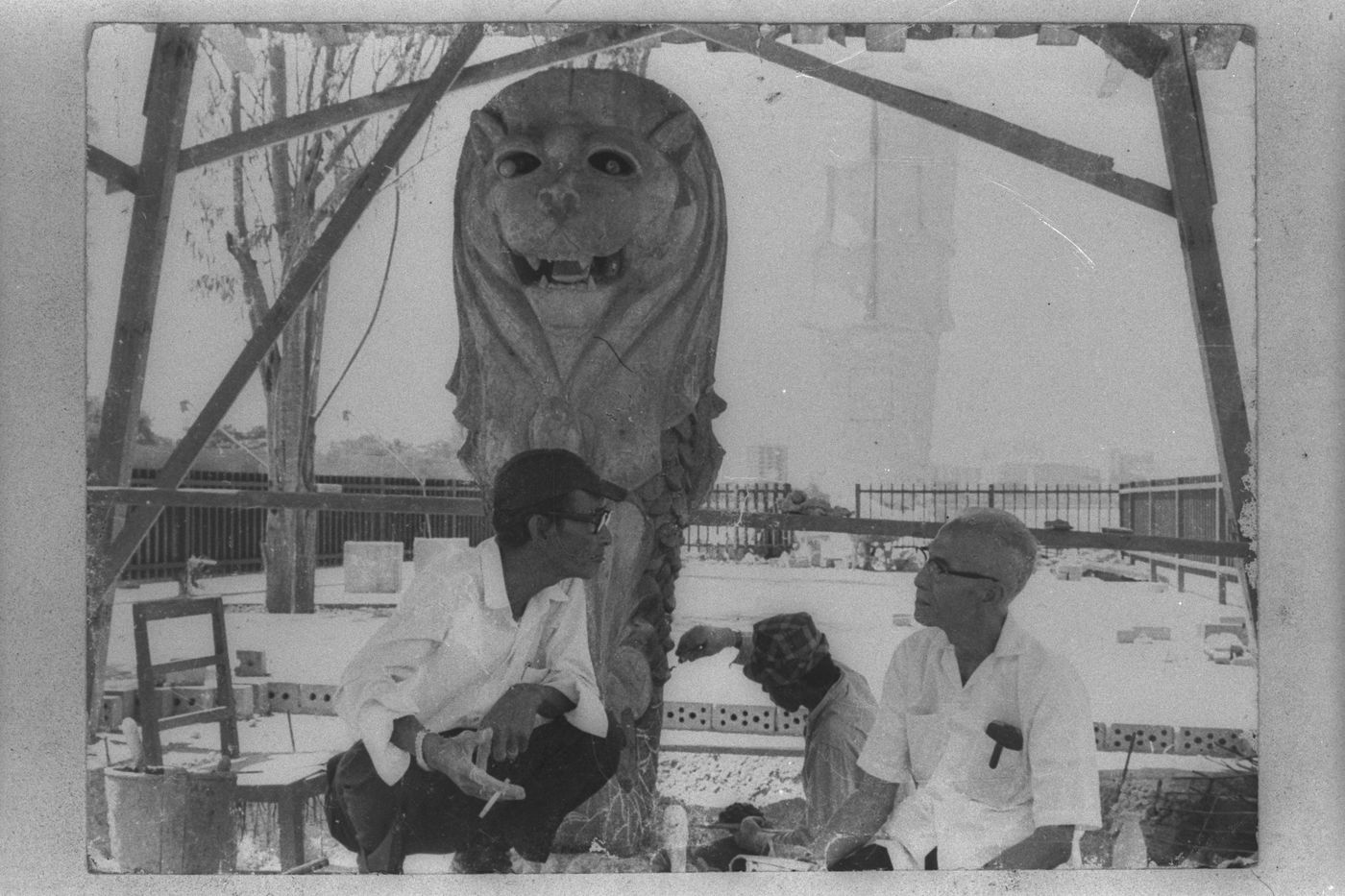 Mr Lim (left) at his worksite with one of the Merlion statues (background) sculpted by him.</br>1972, Lim Nang Seng