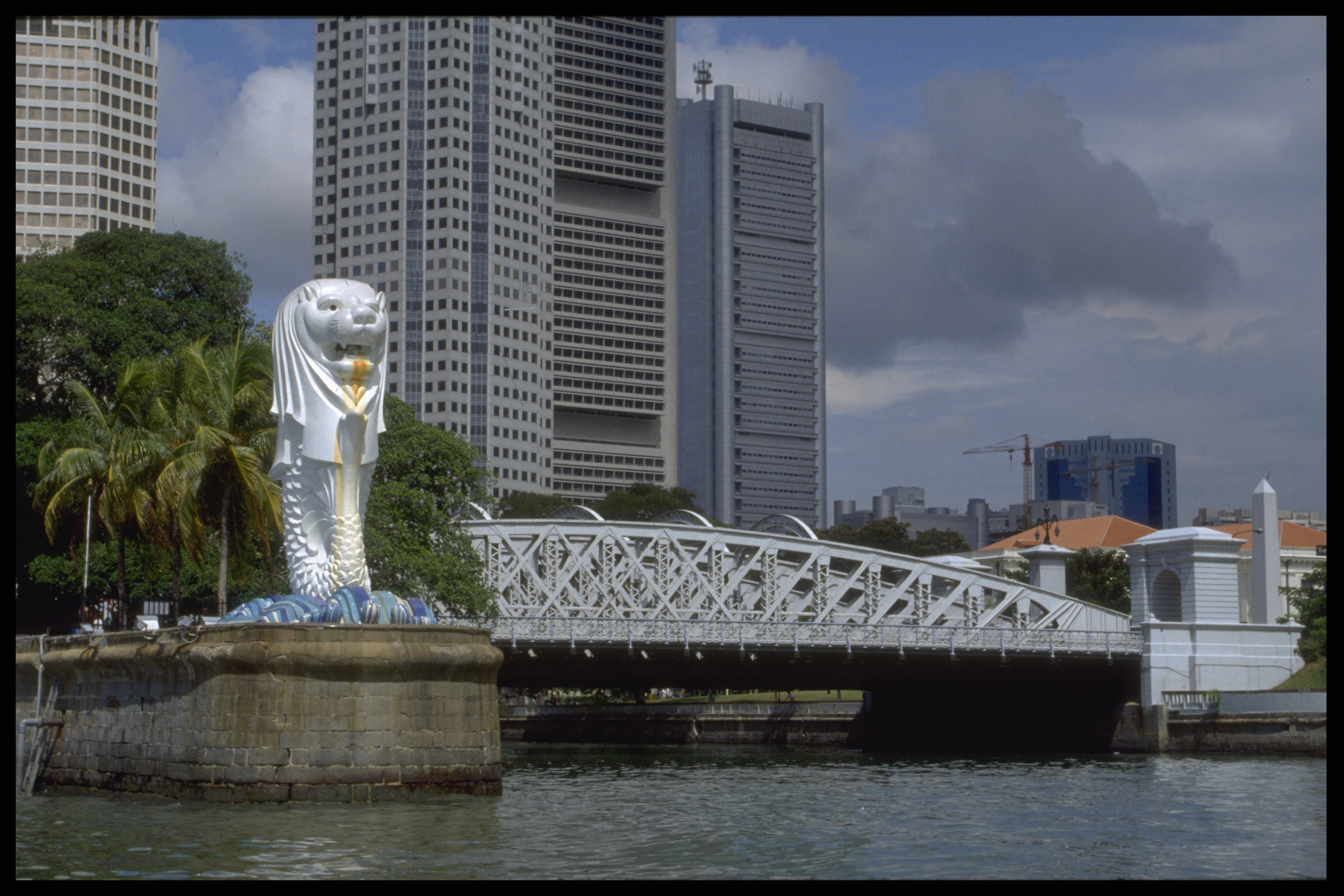 The Merlion Statue against the backdrop of Anderson Bridge and office buildings, before Esplanade Bridge was built.</br>Late 1992, STPB